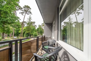 Un balcón con vista a árboles, una silla y una mesa.