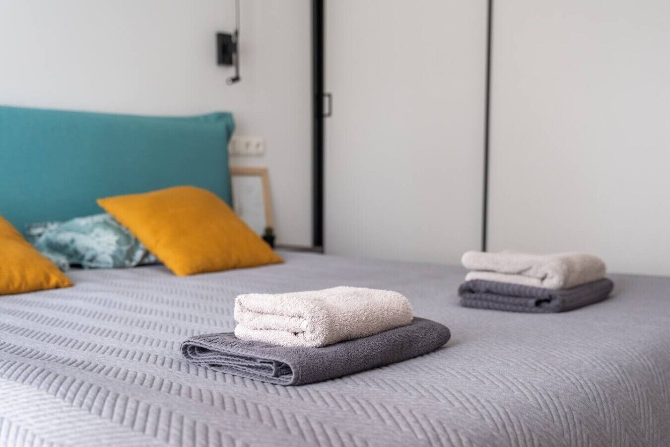 Ein ordentlich bezogenes Bett mit gefalteten Handtüchern und Kissen.