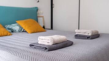 Ein ordentlich bezogenes Bett mit gefalteten Handtüchern und Kissen.
