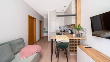 A compact living space with a kitchenette, a dining area, and a seating area with a sofa and chairs.