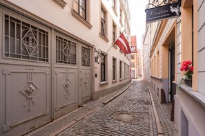 A narrow cobblestone street flanked by buildings with decorative metal grilles on the windows. - Elegant 2-Bedroom 50m² Apartment | Old Town Riga (Riga)
