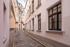 Eine enge Kopfsteinpflasterstraße, gesäumt von Gebäuden mit großen Fenstern und einer Flagge.
