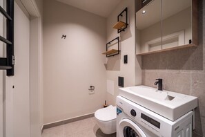 Ein modernes Badezimmer mit Toilette, Waschmaschine und Waschbecken.