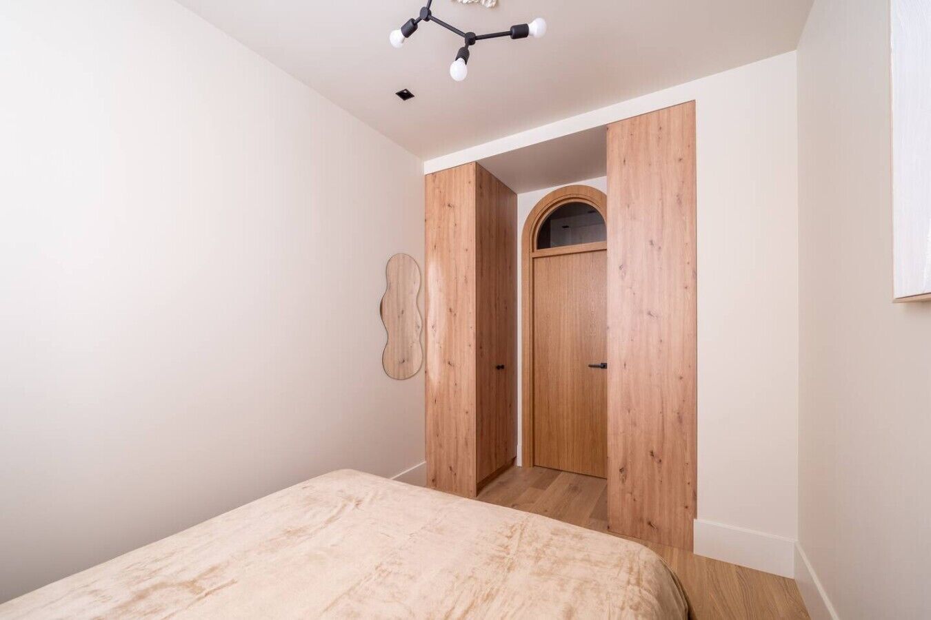 Une chambre à coucher avec un lit, une armoire en bois et un luminaire fixé au plafond.