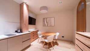 Una cocina moderna con comedor, armarios de madera, una mesa redonda y sillas blancas.