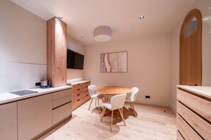 Eine moderne Küche mit Essbereich, Holzschränken, einem runden Tisch und weißen Stühlen.