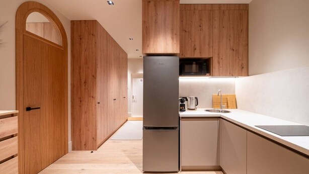 Una cocina moderna con armarios de madera, un refrigerador de acero inoxidable y un microondas.