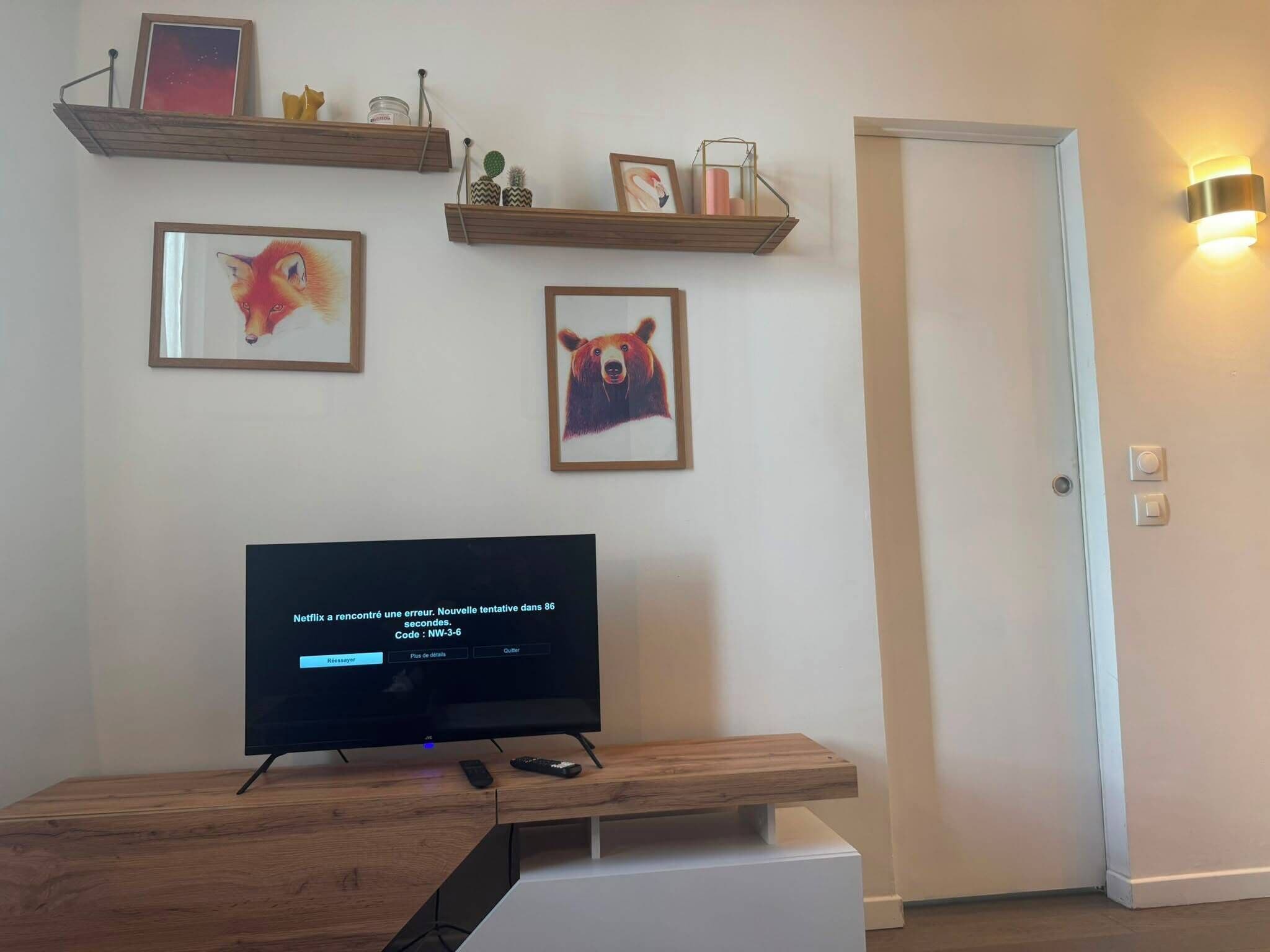 Ein Wohnzimmer mit einem Flachbildfernseher, Holzregalen mit Dekoration und einer Tür.