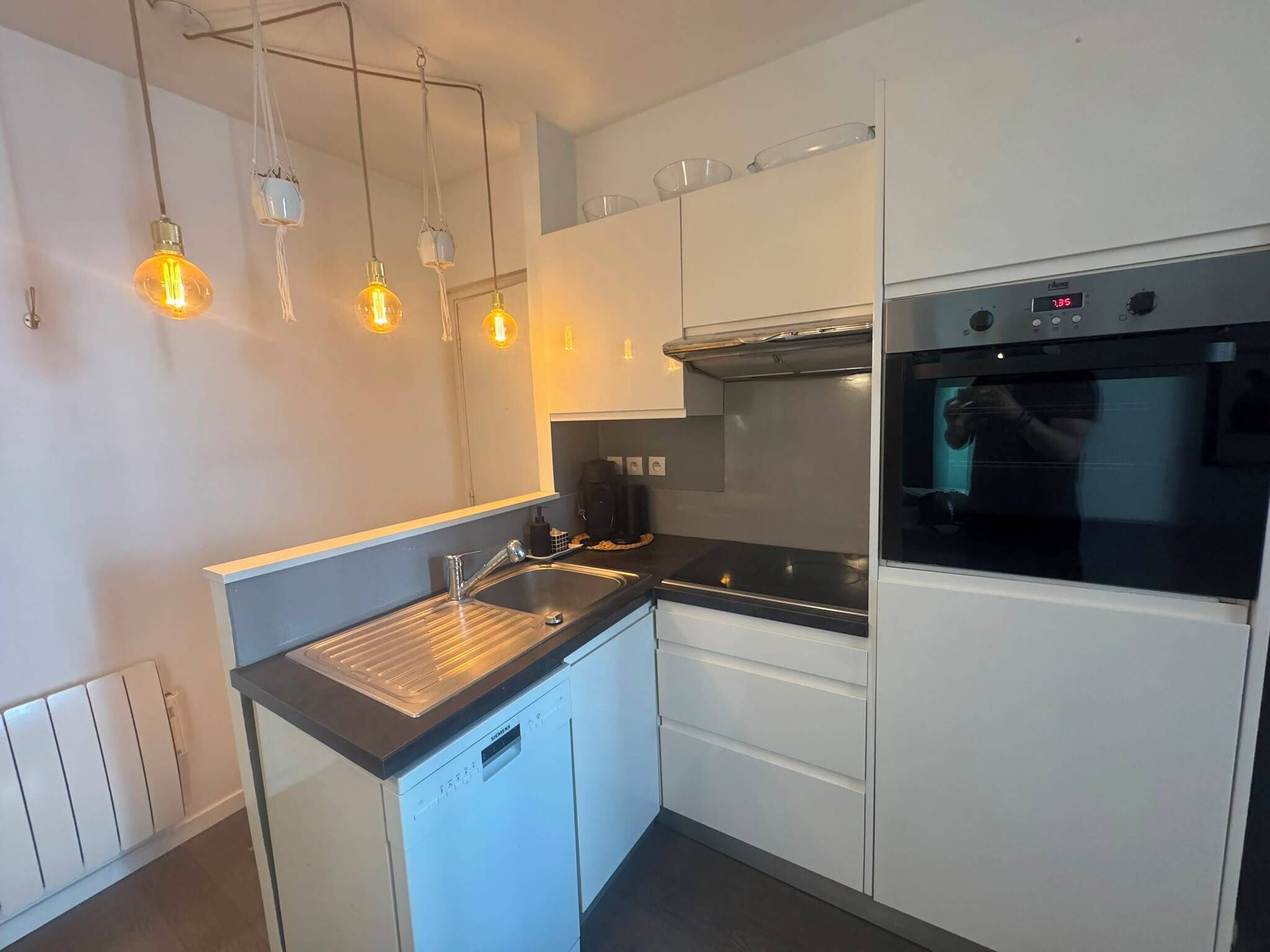 Een moderne keuken met witte kasten, een roestvrijstalen spoelbak en een ingebouwde oven.