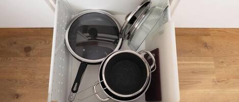 Un cajón de cocina con ollas y sartenes.