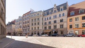 A cobblestone street lined with historic buildings, a pizza restaurant, and parked cars. - Spacious Family Haven in Riga’s Historic Heart (Rīga)