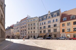 A cobblestone street lined with historic buildings, a pizza restaurant, and parked cars. - Spacious Family Haven in Riga’s Historic Heart (Rīga)