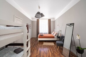 Un dormitorio con literas, una cama individual, un escritorio, una silla, un espejo y una planta en maceta.