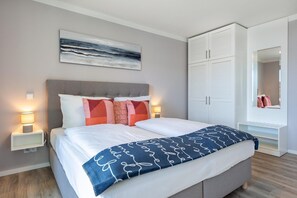 A modern bedroom with a bed, bedside lamps, a large artwork, a wardrobe, and a mirror. - Apartment in Strand- und Parknahe (Lübeck)