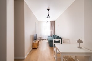 A modern living room with a sofa, a dining table, and a TV. - Artilerijas 1-bedroom apartment | Courtyard View (Riga)