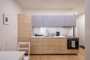 Eine moderne Küche mit hellen Holzschränken, einer weißen Arbeitsplatte und einem eingebauten Backofen.