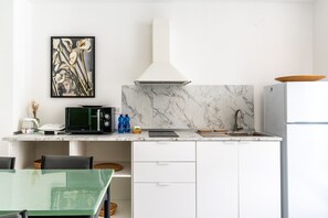 A modern kitchen with a marble backsplash, a microwave, a sink, and a refrigerator. - Dinologo Modern Flat by Wonderful Italy (Syracuse)