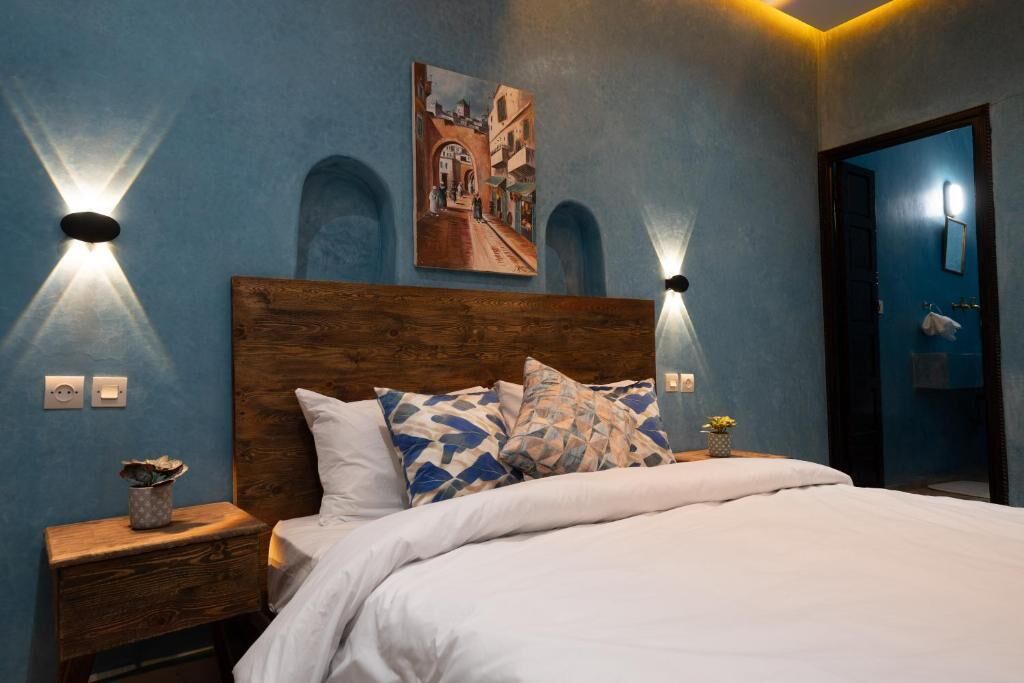 Ein Schlafzimmer mit einem Holz-Kopfteil, einem Bett mit weißer Bettwäsche, zwei Wandlampen und einem Gemälde über dem Bett.