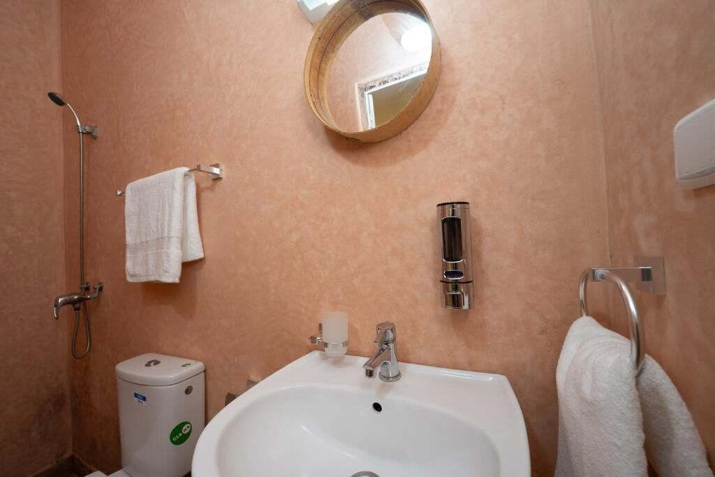 Une salle de bain équipée d’un lavabo, d’un miroir, d’un porte-serviettes et d’une douchette à main.