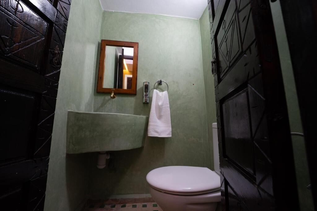 Une salle de bain avec des toilettes, un lavabo et un miroir.