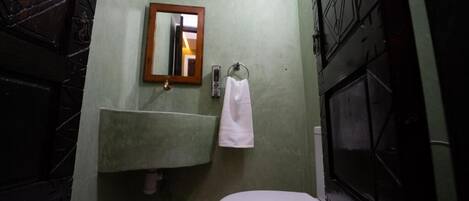 A bathroom with a toilet, a sink, and a mirror.