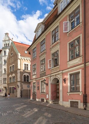 Una strada fiancheggiata da edifici storici, tra cui un palazzo con facciata rossa e stile architettonico tradizionale.