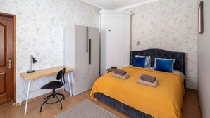 Ein Schlafzimmer mit Bett, Schreibtisch, Stuhl, Kleiderschrank und einer Tür.