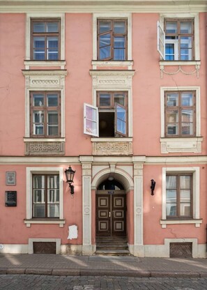 A pink building with a central entrance, multiple windows, and a door with a sign above it. - Heart of Old Town TOP location 1-Bedroom Apartment (Riga)