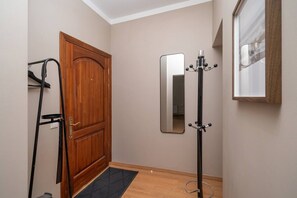 A hallway with a wooden door, a coat rack, a mirror, and a black floor mat. - Heart of Old Town TOP location 1-Bedroom Apartment (Riga)