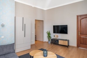 A modern living room with a sofa, a coffee table, a TV, and a wooden cabinet. - Heart of Old Town TOP location 1-Bedroom Apartment (Riga)