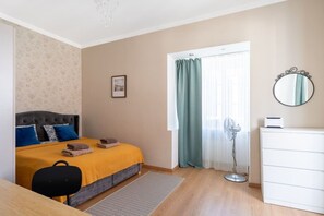 A bedroom with a bed, bedside table, dresser, and a standing fan. - Heart of Old Town TOP location 1-Bedroom Apartment (Riga)