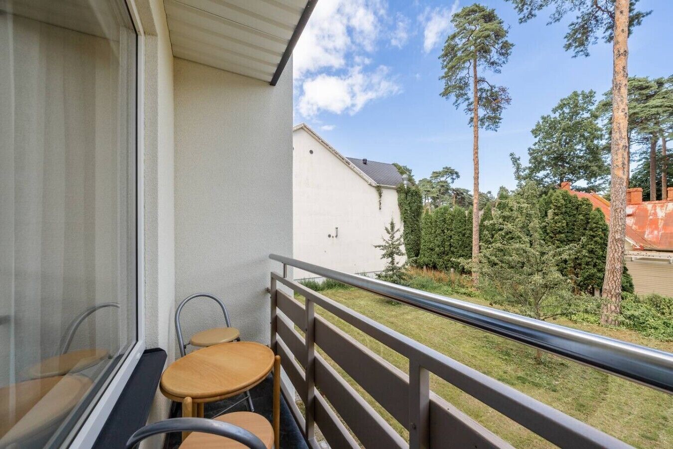 A balcony with a view of a residential area, including trees and a building.