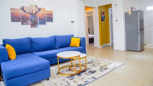 A modern living room with a blue sofa, a round coffee table, and a rug.