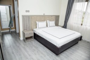 Un dormitorio moderno con una cama grande, una mesita de noche y un ventanal con cortinas.