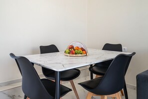 Een eettafel met een marmeren blad, omringd door vier zwarte stoelen met houten poten.