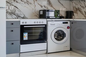 Een compacte keuken met een ingebouwde oven, magnetron en wasmachine.