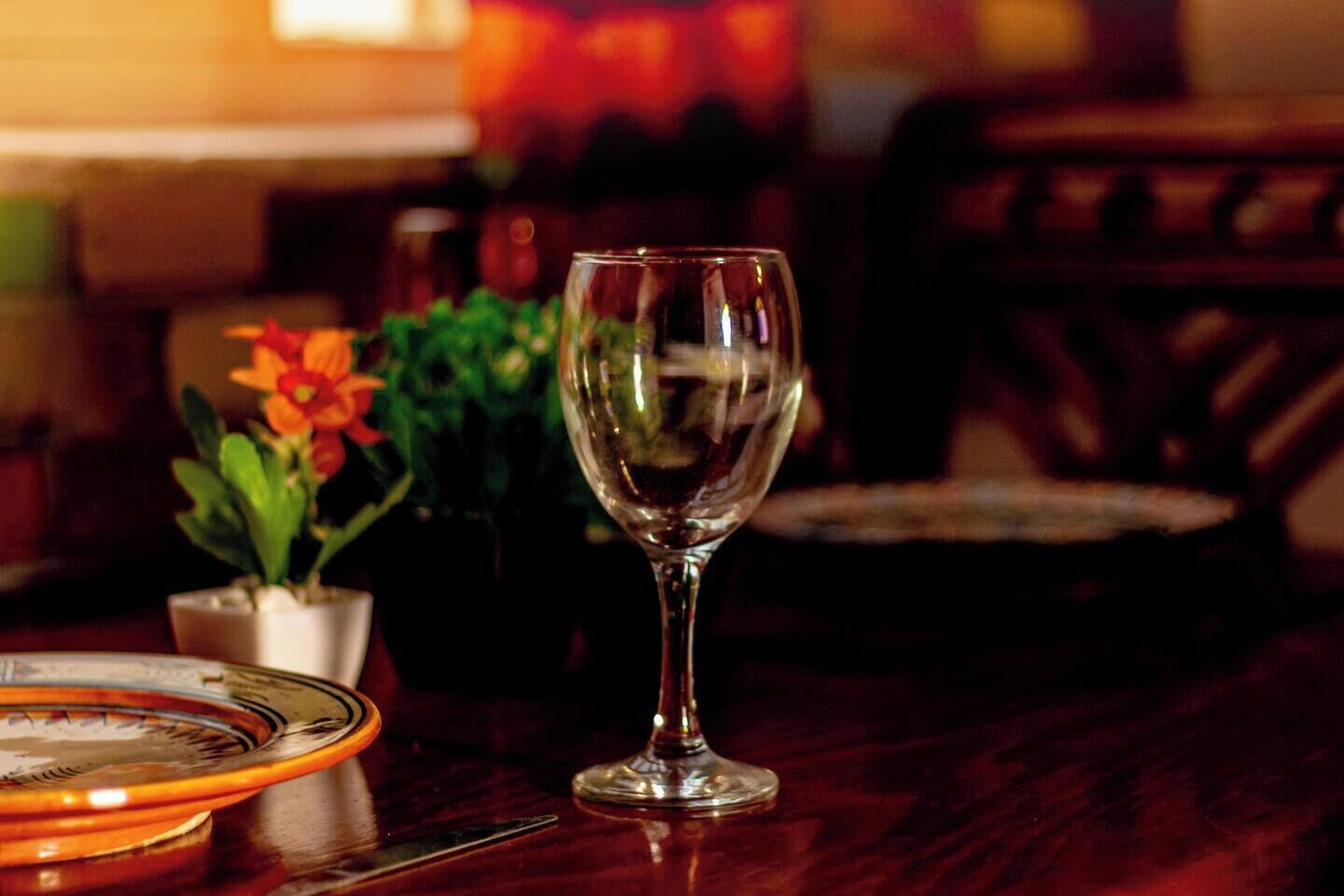 Une table à manger avec un verre à vin, des assiettes et une plante en pot.
