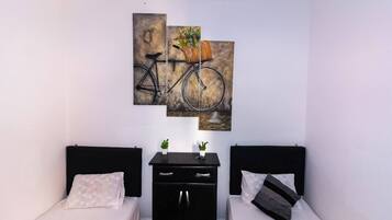 Quarto com duas camas, uma escrivaninha e um quadro na parede de uma bicicleta.