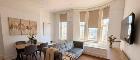 A room with a dining table, chairs, a sofa, and a television.