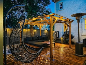 An outdoor patio with a hanging chair, a wooden pergola, and a barbecue grill. - Beautiful modern 2Bdr sunny home with French decor (Hamilton)
