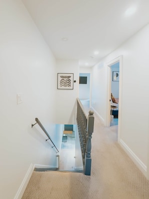 A staircase with a handrail, carpeted steps, and a door leading to another room. - Beautiful modern 2Bdr sunny home with French decor (Hamilton)