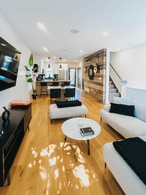 A modern living room with a sofa, coffee table, and a TV. - Beautiful modern 2Bdr sunny home with French decor (Hamilton)