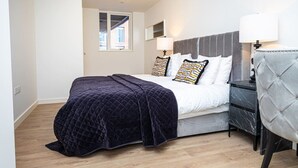 A bedroom with a bed, bedside lamps, a chair, and a window. - Birmingham City Retreat No 117 (Birmingham)