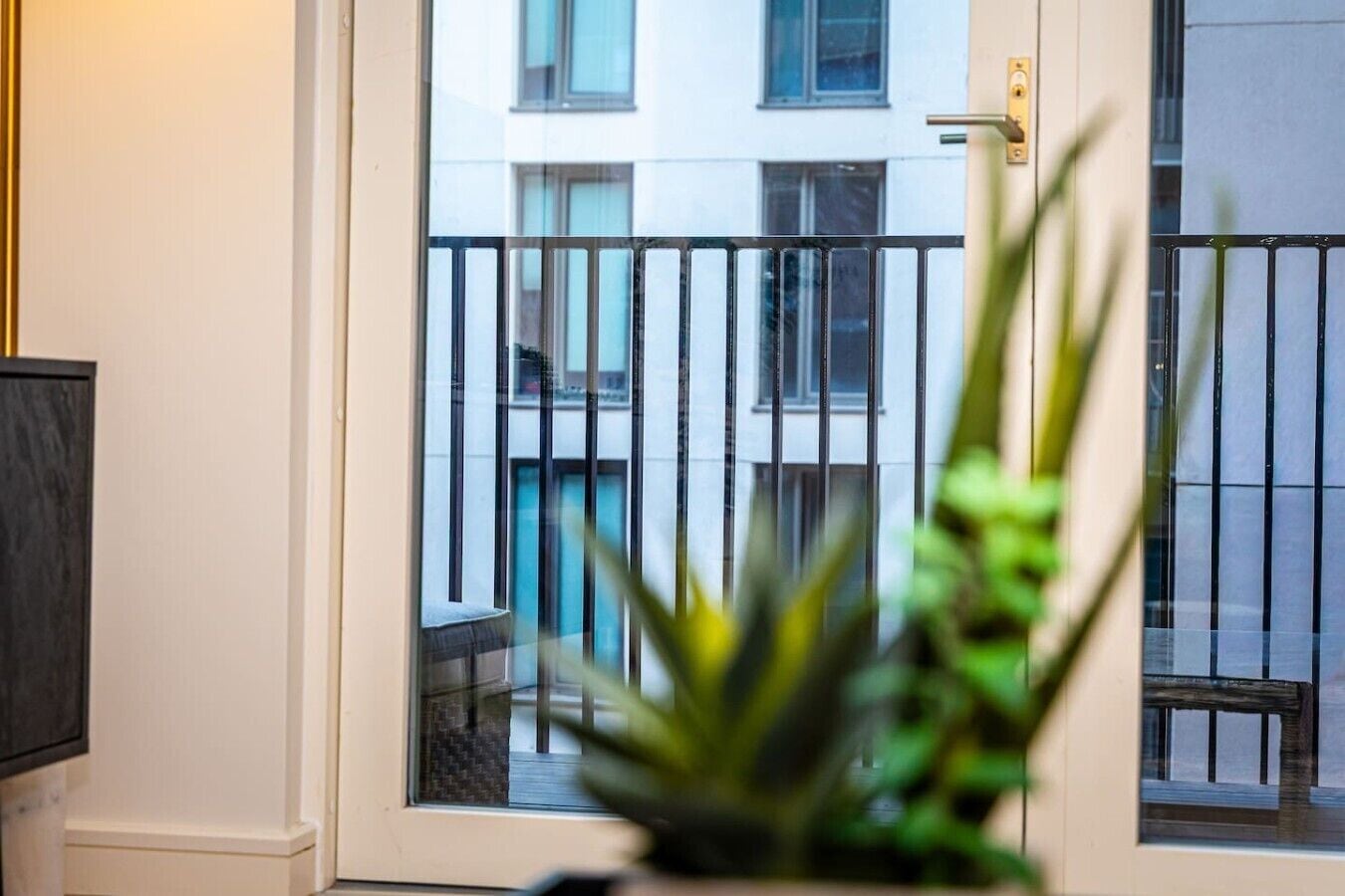 A door with a glass panel, a metal gate, and a view of a building with windows.