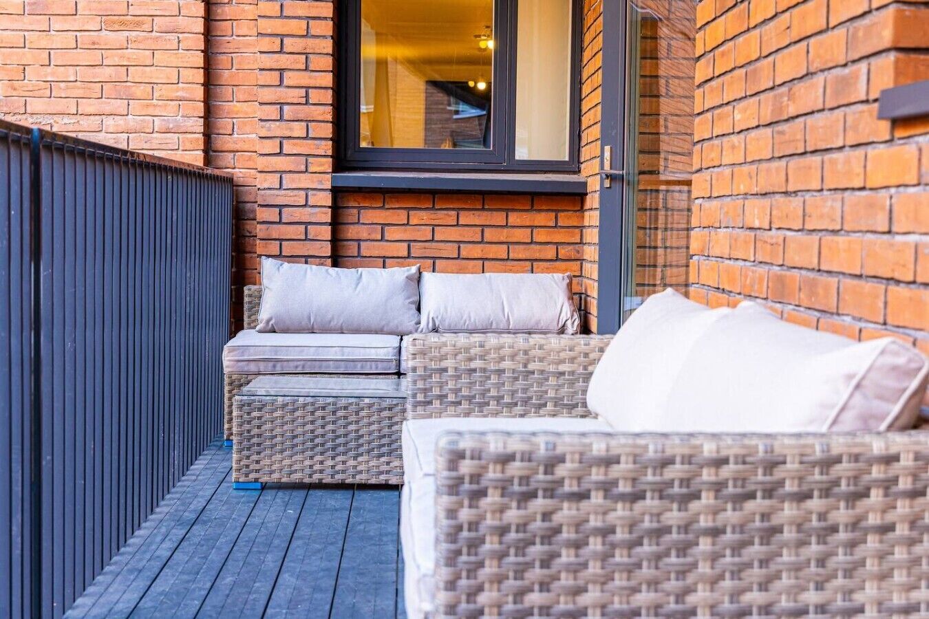 A balcony with wicker furniture and a brick wall.