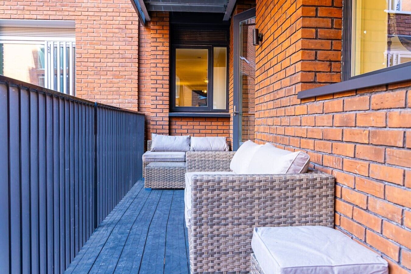 A balcony with wicker furniture and a brick wall.