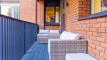A balcony with wicker furniture and a brick wall.