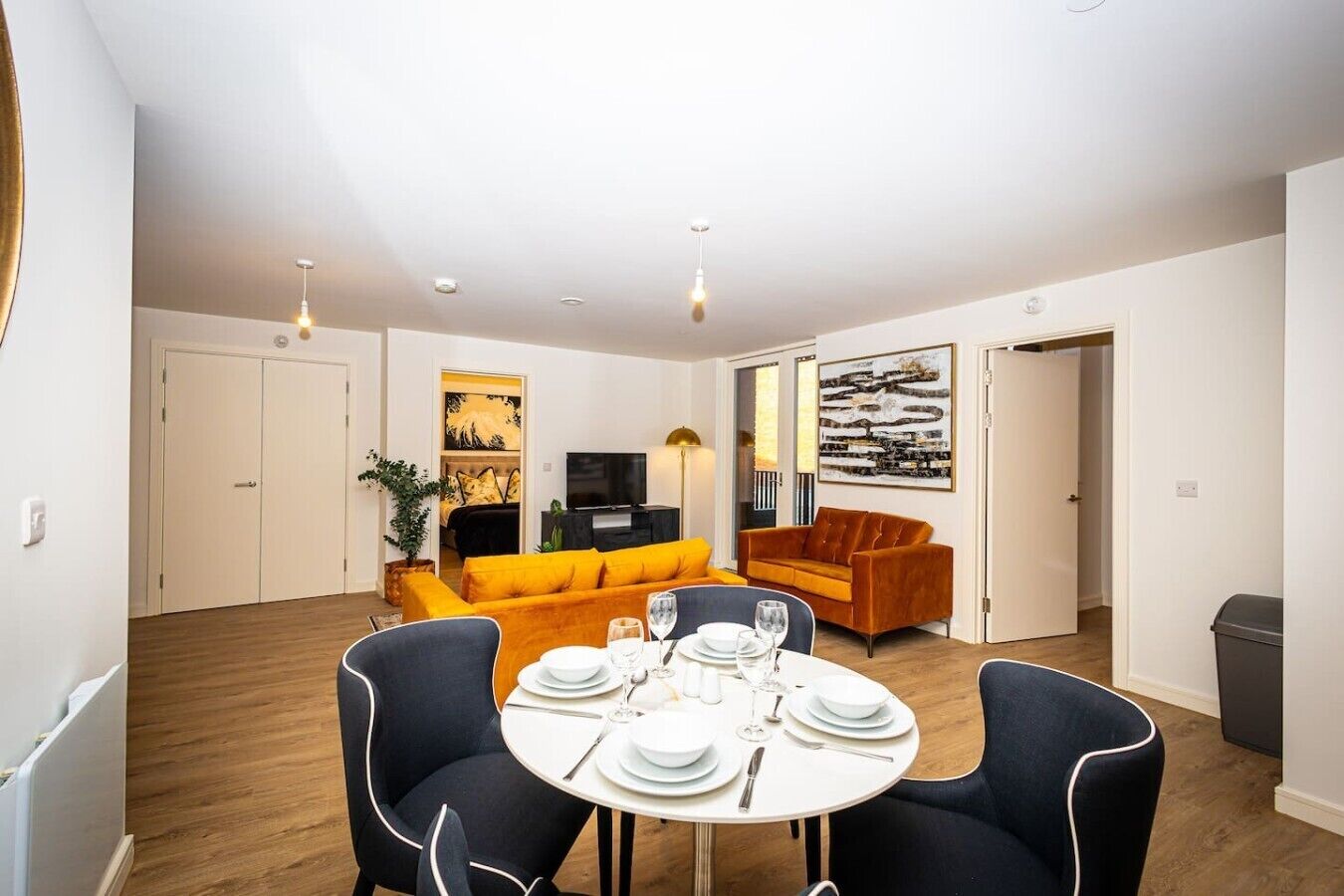 A modern living room with a dining area, featuring a sofa, a coffee table, and a TV.