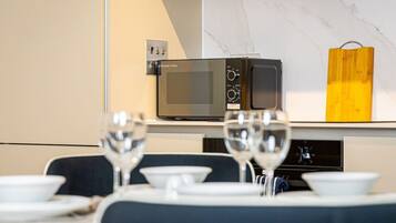 A dining area with a microwave, a wooden block, and a wine glass on a table.