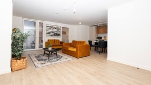 A modern living room with a sofa, coffee table, and dining area with chairs. - Birmingham City Retreat No 117 (Birmingham)
